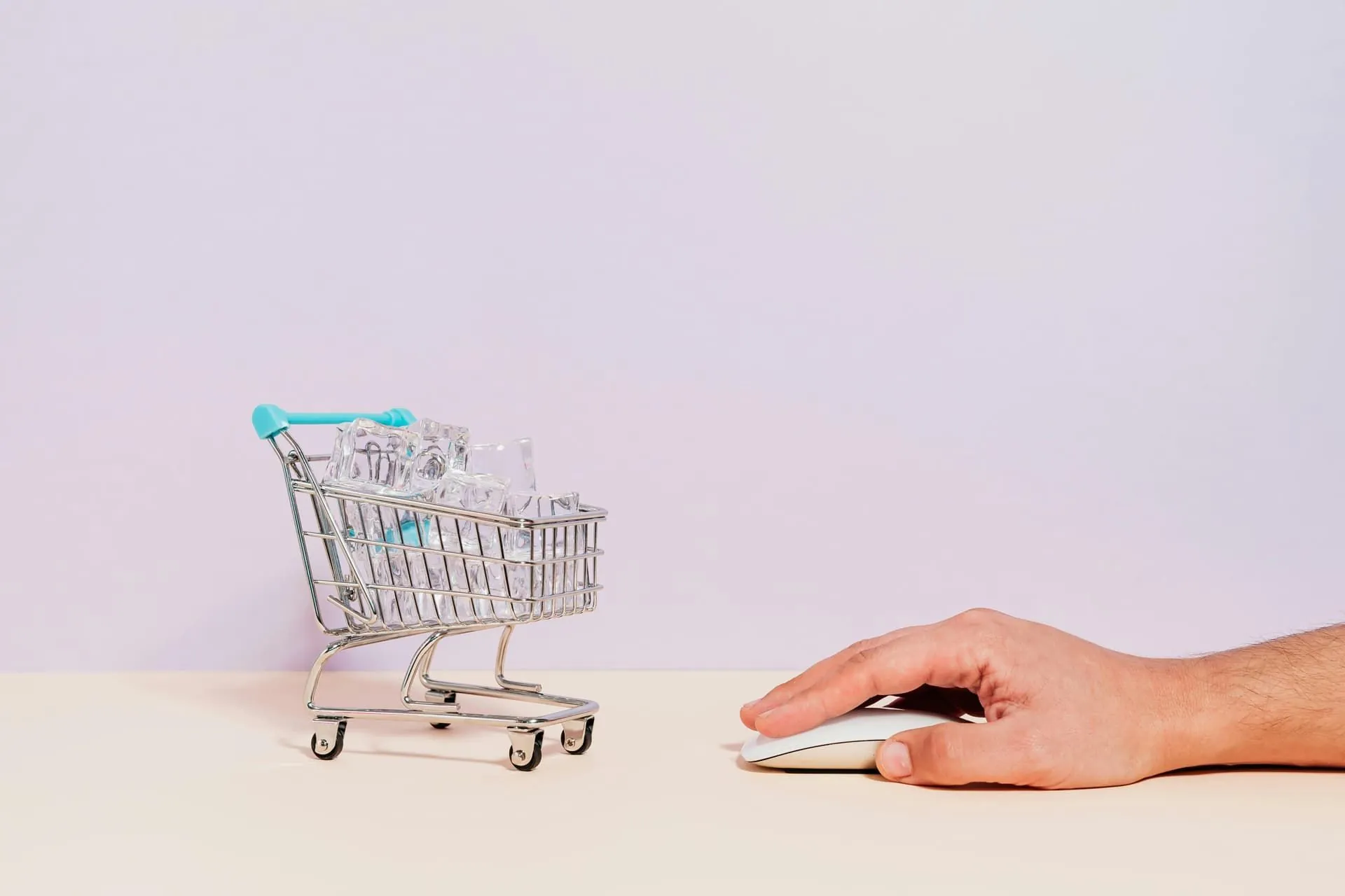 Miniature shopping cart next to a hand using a computer mouse